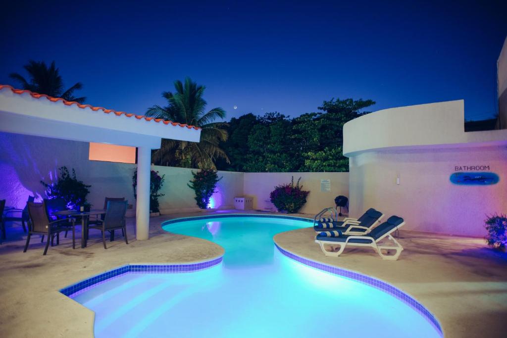 - une piscine de nuit avec des chaises et une table dans l'établissement Aquatech Villas DeRosa Resort, à Akumal
