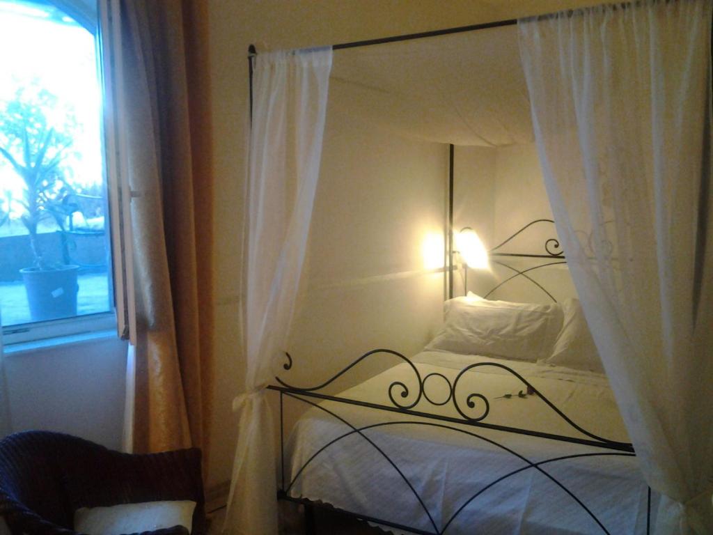 1 dormitorio con cama con dosel y ventana en Casa in collina "la farfalla", en Riparbella