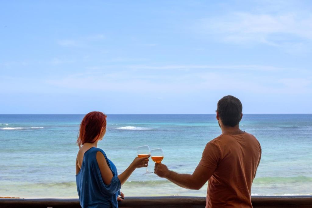 Ein Mann und eine Frau mit einem Glas Wein am Strand. in der Unterkunft Aquatech Villas DeRosa Resort in Akumal