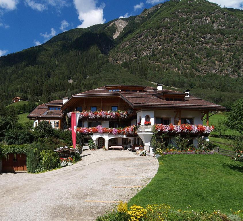a building with flowers in front of a mountain at Haus Tirol in Molini di Tures