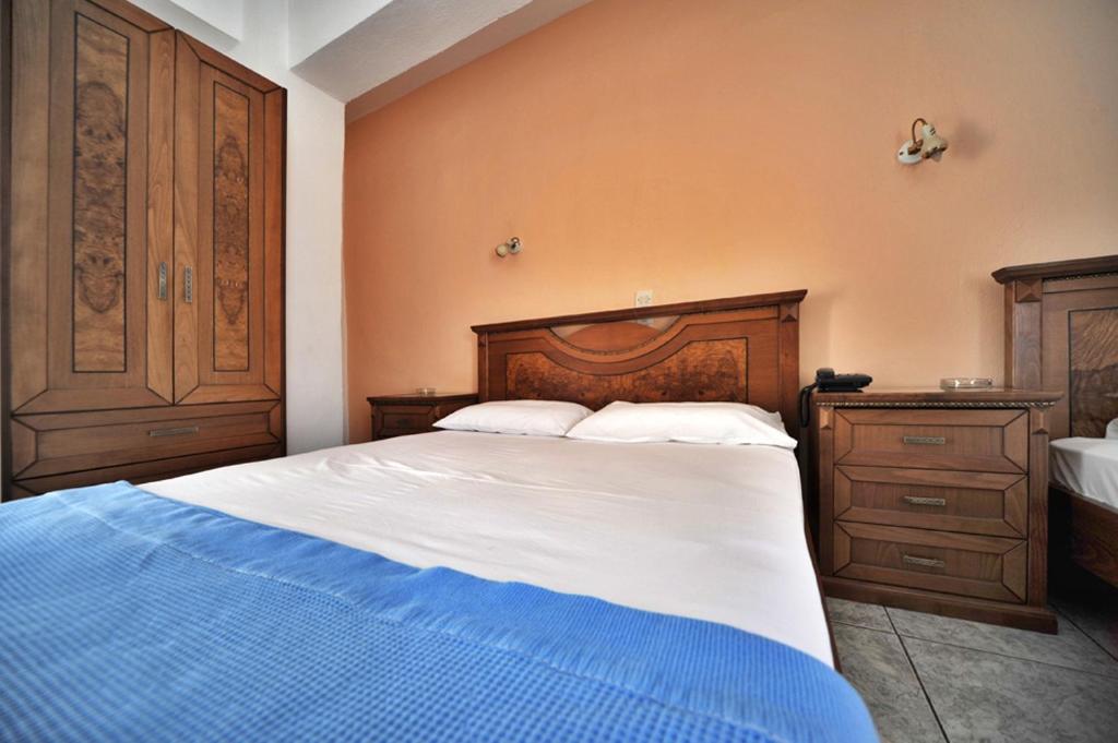 a bedroom with a large bed with a wooden headboard at Hotel Jason in Volos
