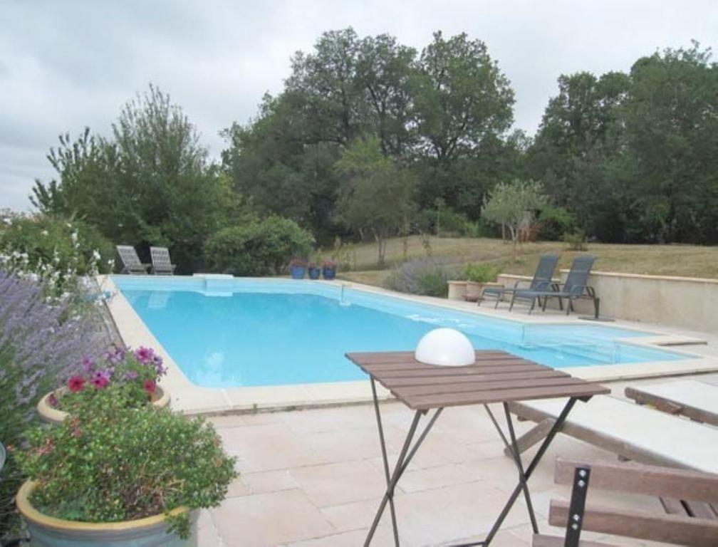 a swimming pool with a wooden table and a picnic table at Le Fraysse in Montdurausse