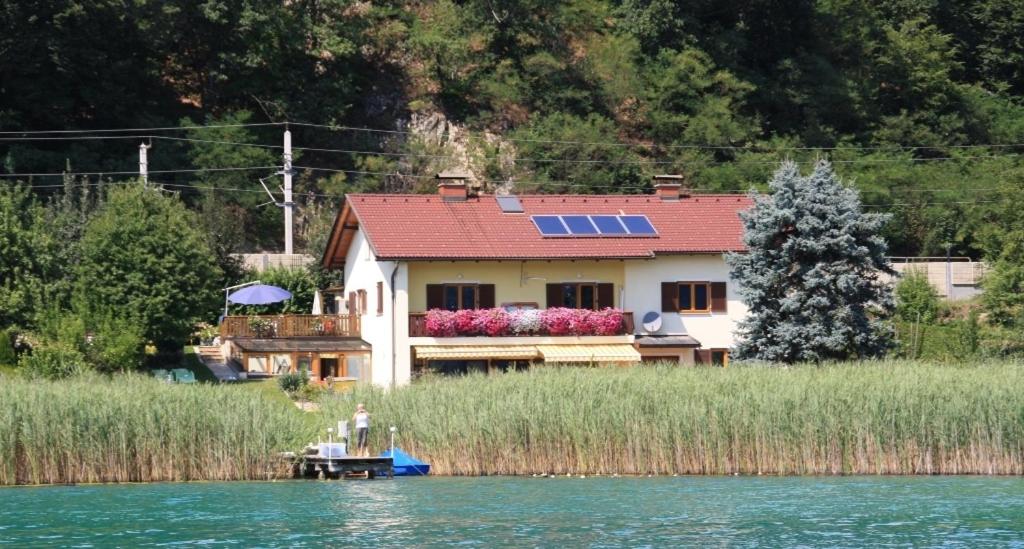 a house on the shore of a lake with a boat at Haus Babin in Techelsberg am Worthersee