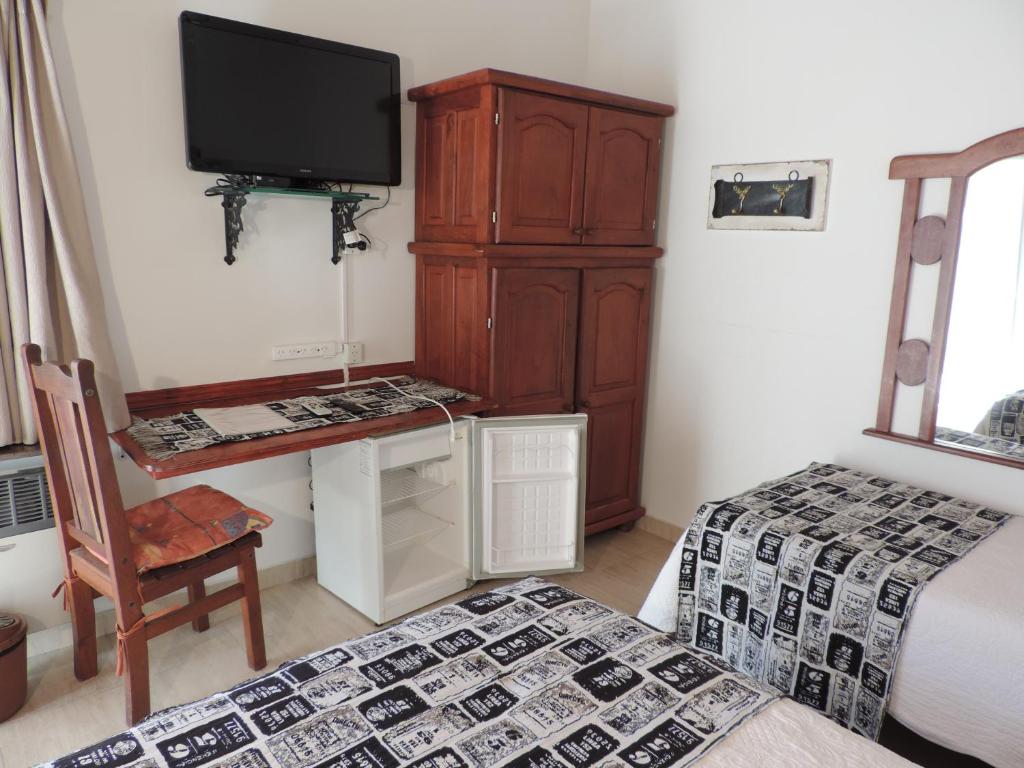 1 dormitorio con TV, escritorio y cama en Hosteria Las Piedras en Puerto Madryn