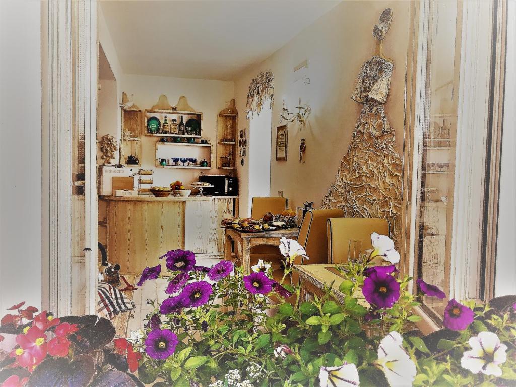 オリスターノにあるDomo All'Antico Borgoの紫の花が咲くリビングルーム、キッチンが備わります。