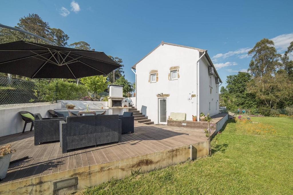 una casa blanca con una sombrilla en la cubierta en Casa do Porto Carreiro, en Oliveira de Azemeis