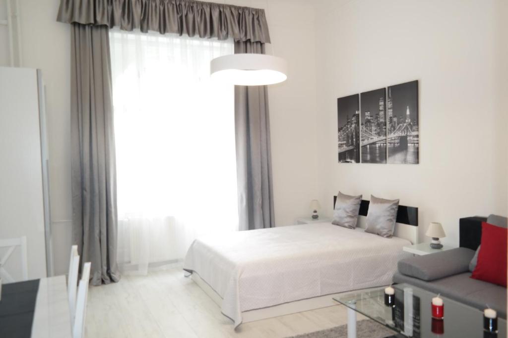 ブダペストにあるHestia Apartmentの白いベッドルーム(ベッド1台、ソファ付)