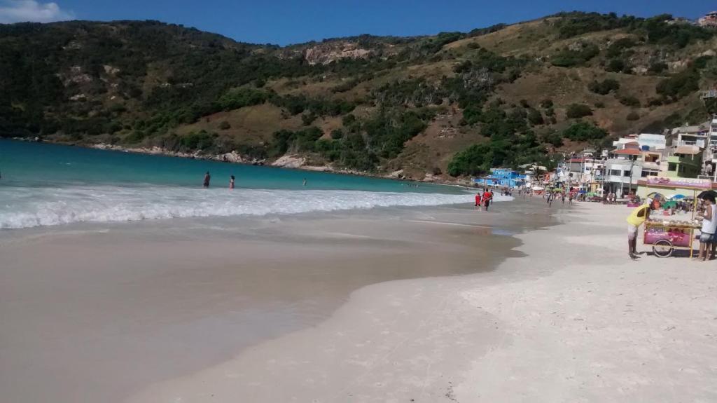 un grupo de personas en una playa con el agua en Prainha Aconchegante apto de quarto e sala com vista para o mar en Arraial do Cabo