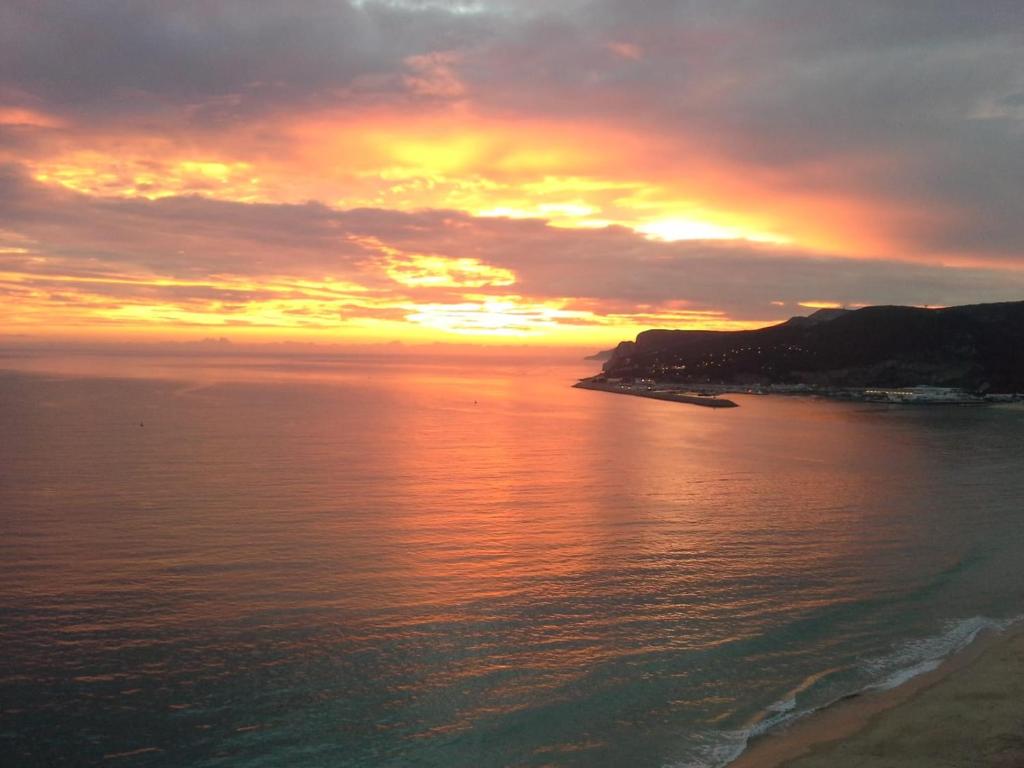 einen Sonnenuntergang über einem Wasserkörper mit einem Strand in der Unterkunft Sesimbra Sun Bay in Sesimbra