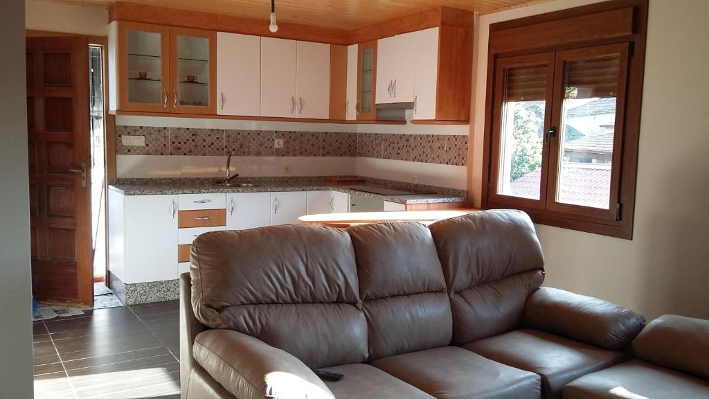 a living room with a leather couch in a kitchen at apartamento en el rural Mariela in Covelo