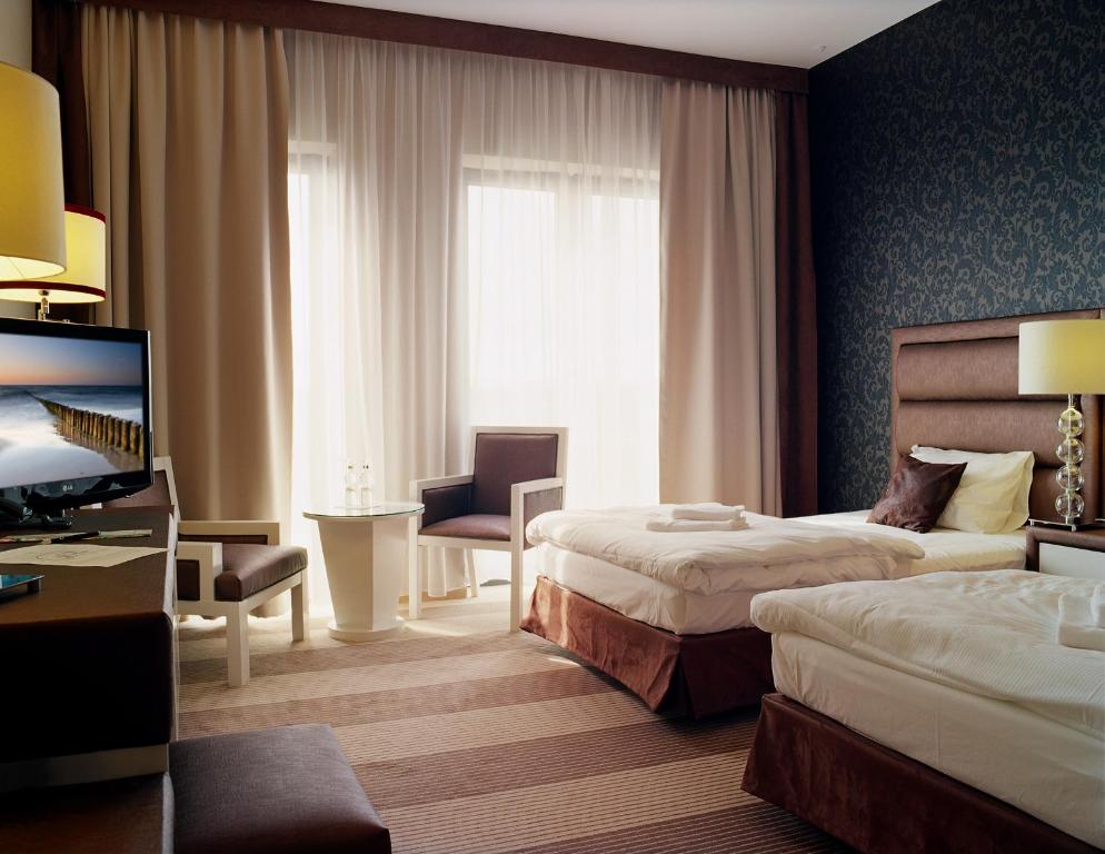 a hotel room with two beds and a desk and a television at Hotel Alhar in Lubliniec