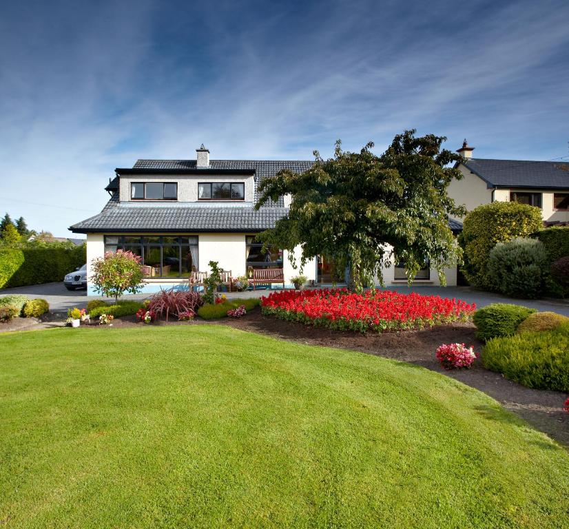 una casa con un gran patio con flores rojas en Shelmalier House, en Athlone