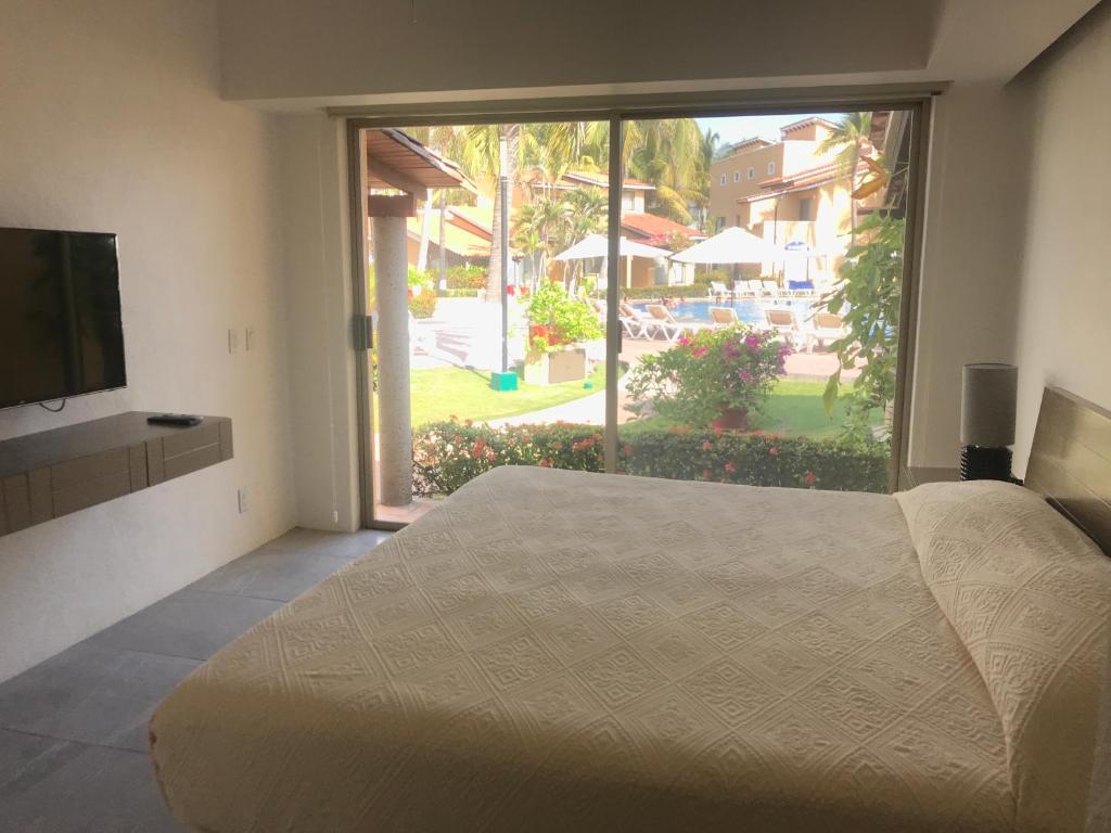 1 dormitorio con 1 cama, TV y ventana en Villa 18 Con Playa 3 Recamaras dentro de Hotel en Ixtapa en Ixtapa