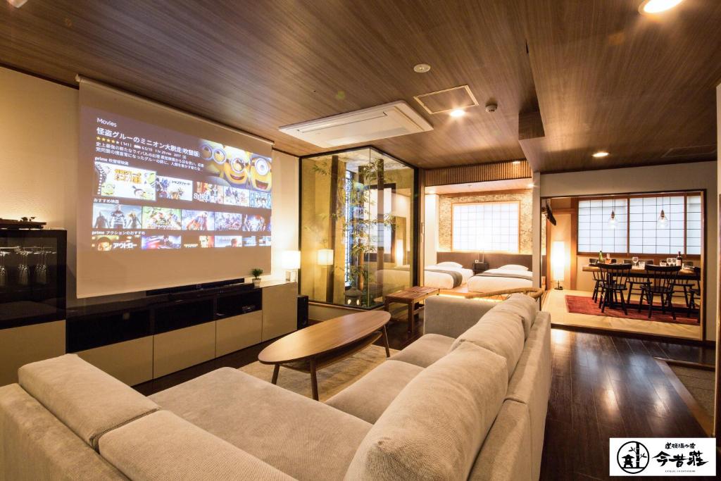 een woonkamer met een bank en een groot scherm bij Konjaku-So Dotonbori Penthouse Stay in Osaka