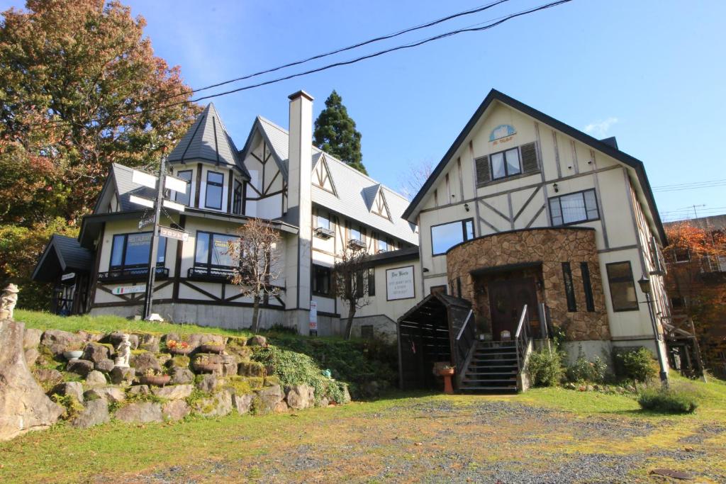 a large white house with a stone wall at Petit Resort Hotel Der Barte in Zao Onsen