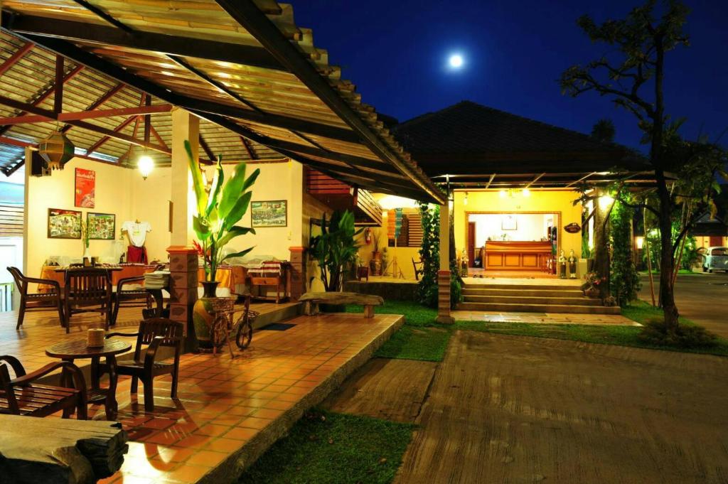 an outdoor patio with tables and chairs at night at Baan Kiang Chan Resort in Mae Sot