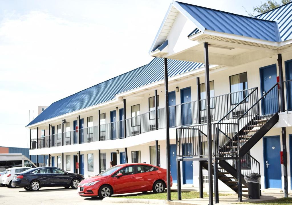 un bâtiment avec une voiture rouge garée devant lui dans l'établissement Bayfront Inn Biloxi, à Biloxi