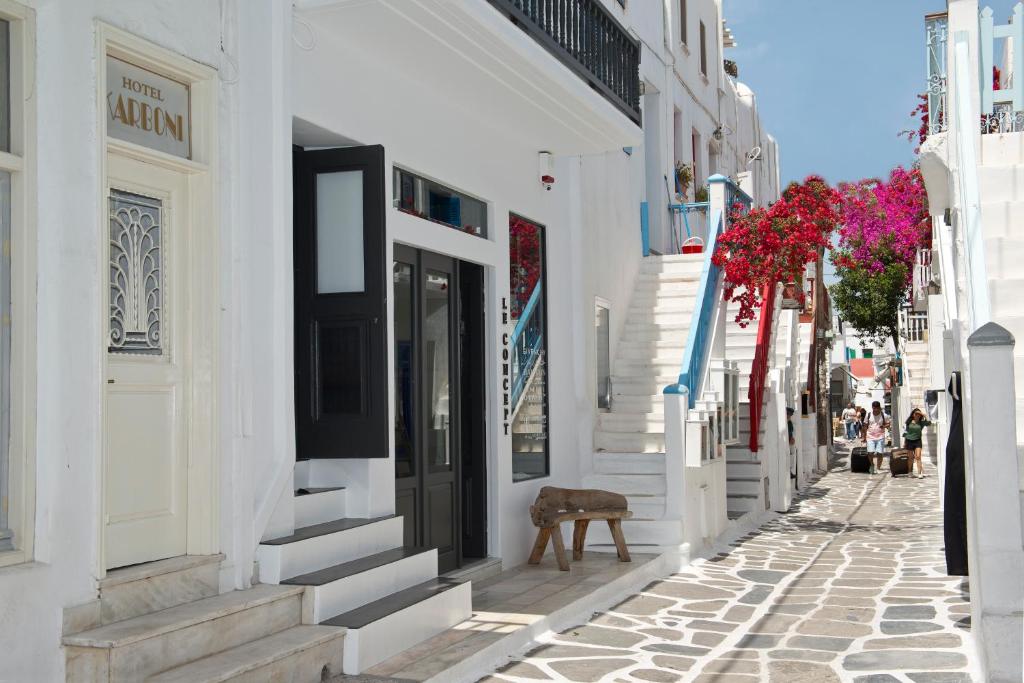 una calle estrecha con edificios blancos y flores en Karboni Hotel, en Mykonos ciudad