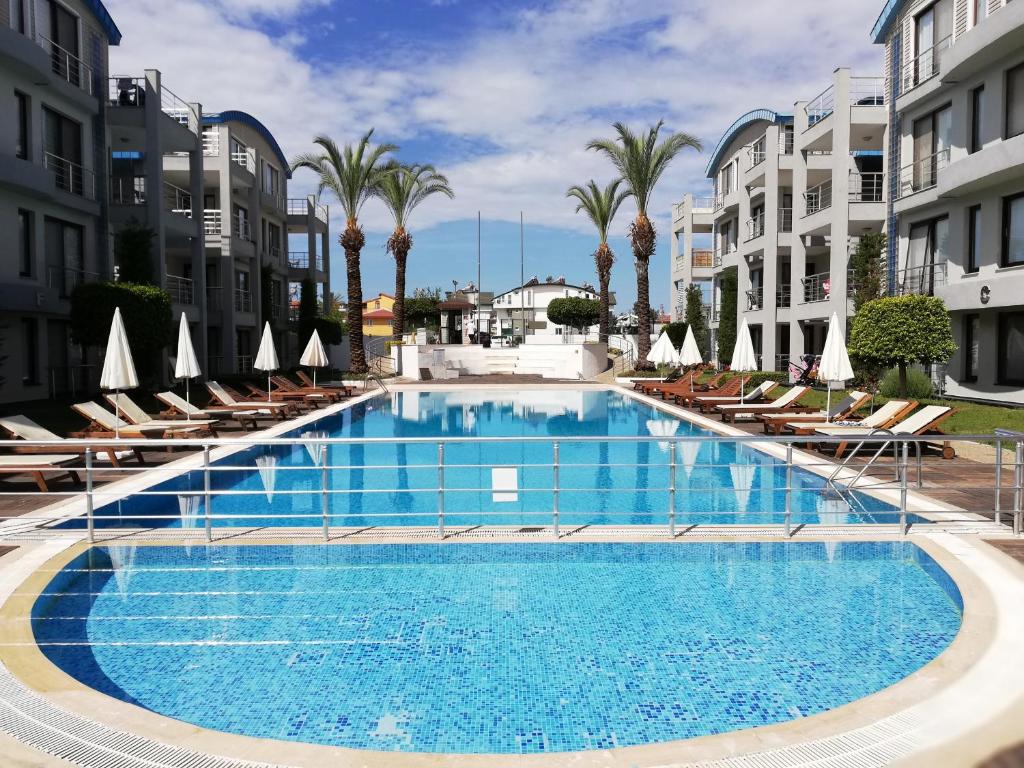 a large swimming pool with chairs and palm trees at Side Garden Residence in Side