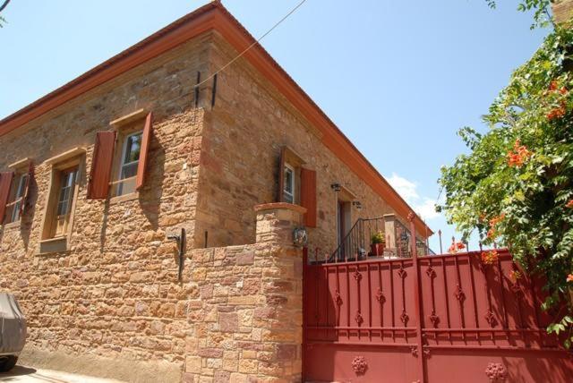 una casa de ladrillo con una valla roja delante de ella en Krini Rooms en Thymianá