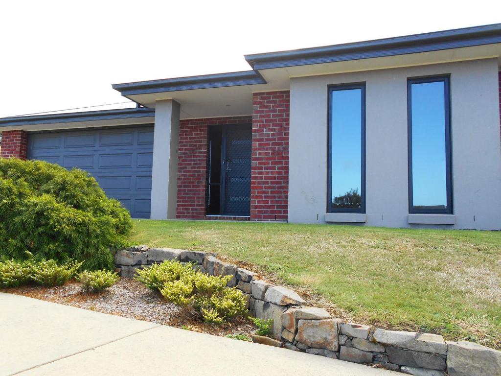 une maison avec des fenêtres bleues et une cour dans l'établissement Plovers Rest, à Inverloch