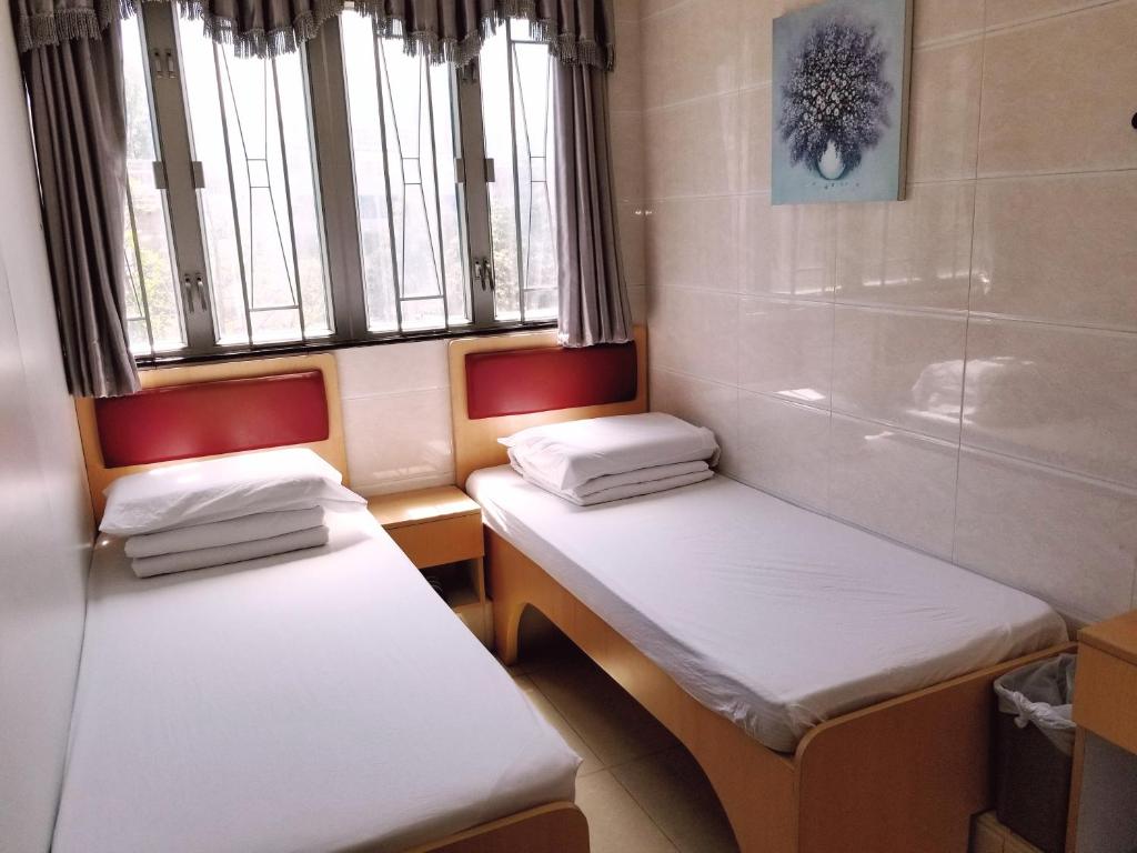 two twin beds in a room with a window at Asia Travel House in Hong Kong
