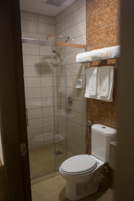a bathroom with a toilet and a shower with towels at Al Afiah Hotel in Bandar Seri Begawan