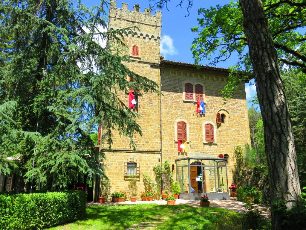 un grand bâtiment en briques avec des fenêtres rouges et une tour dans l'établissement Castello Cortevecchio, à Gubbio