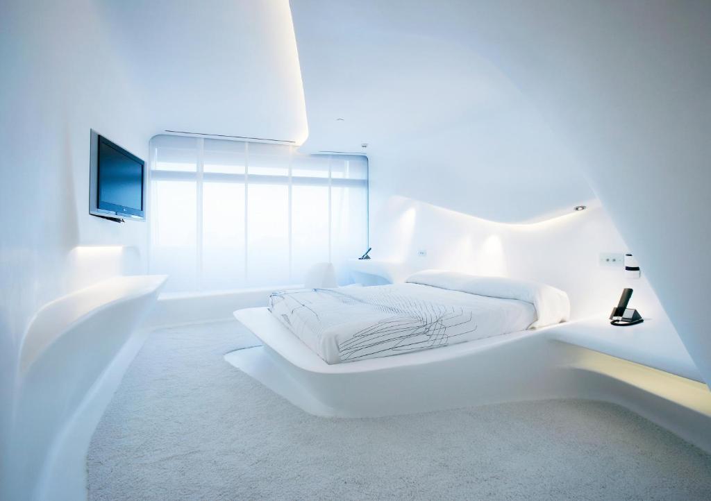 
a bathroom with a white bed and a white wall at Hotel Puerta America in Madrid
