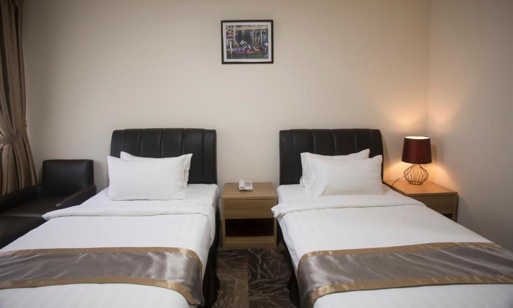 a hotel room with two beds and a table at Al Afiah Hotel in Bandar Seri Begawan