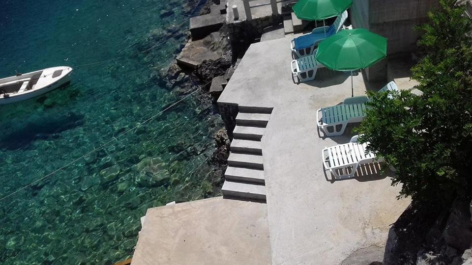 a group of chairs and umbrellas next to the water at Apartments Šojka in Sobra