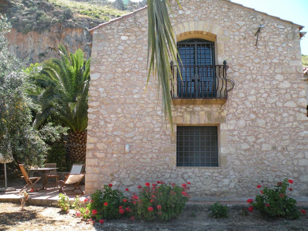 un edificio de piedra con balcón y flores en the ancient sicilian house near zingaro reserve Scopello, en Scopello