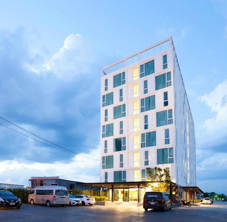een hoog wit gebouw met auto's geparkeerd op een parkeerplaats bij อีซี่โฮเทล 2 in Lamphun
