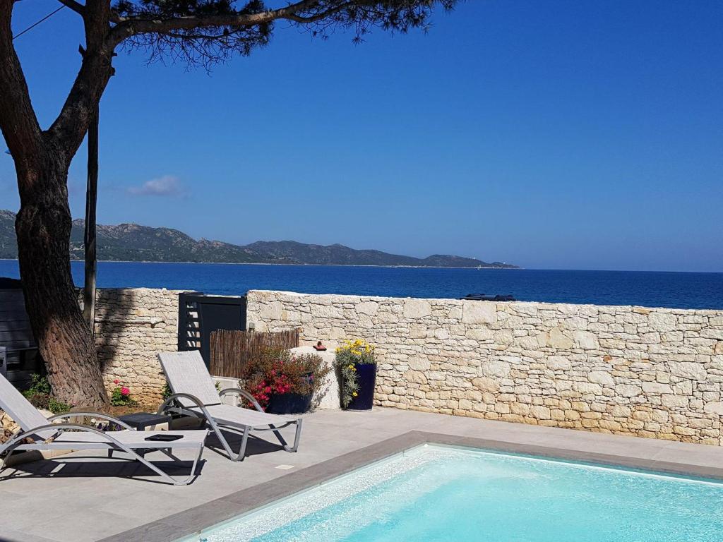 a swimming pool with two chairs and a stone wall at Appart Bleu Azur in Saint-Florent