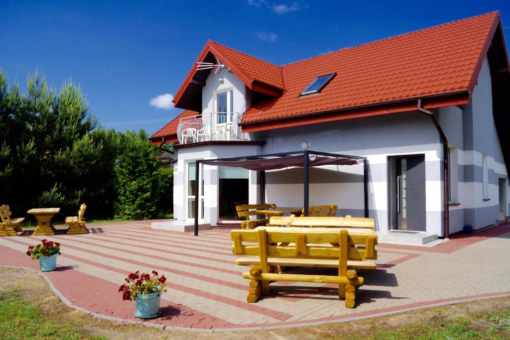 un patio con bancos y mesas y un edificio en White Lake Villa, en Gostynin