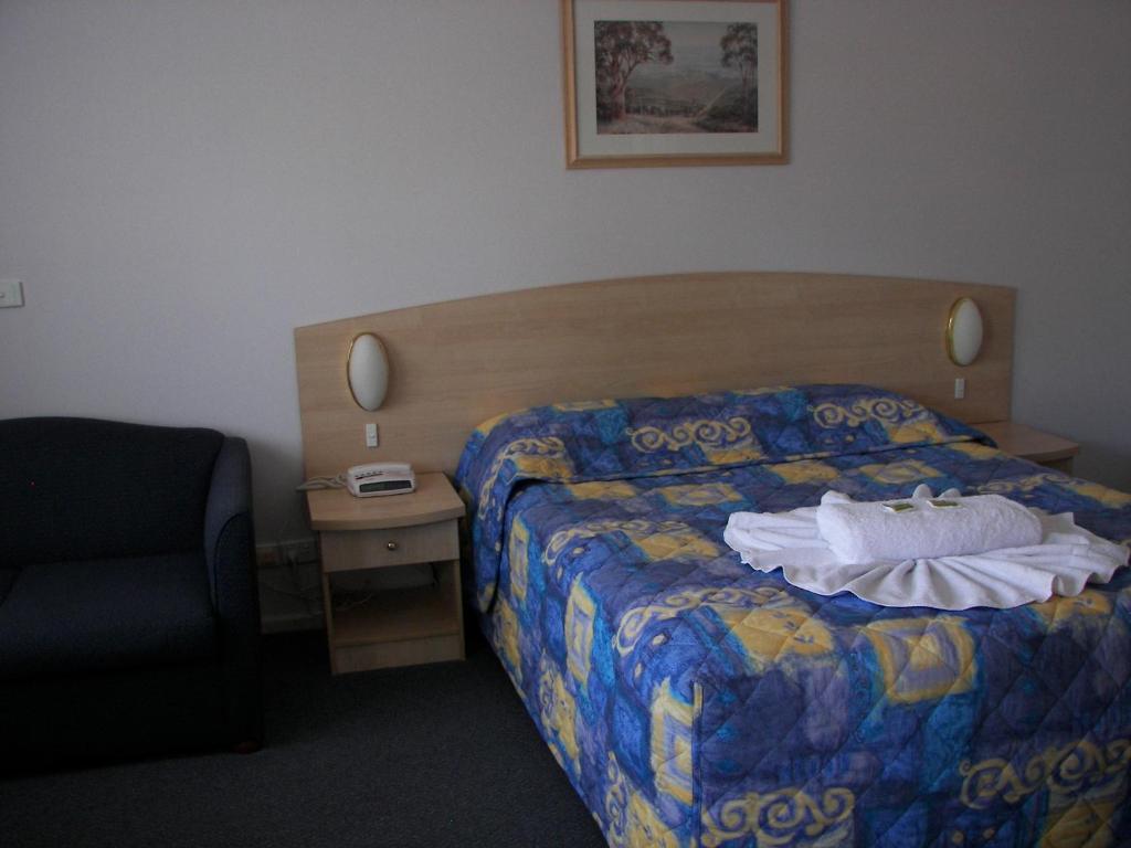 um quarto de hotel com uma cama e uma cadeira em Bega Southtown Motor Inn em Bega