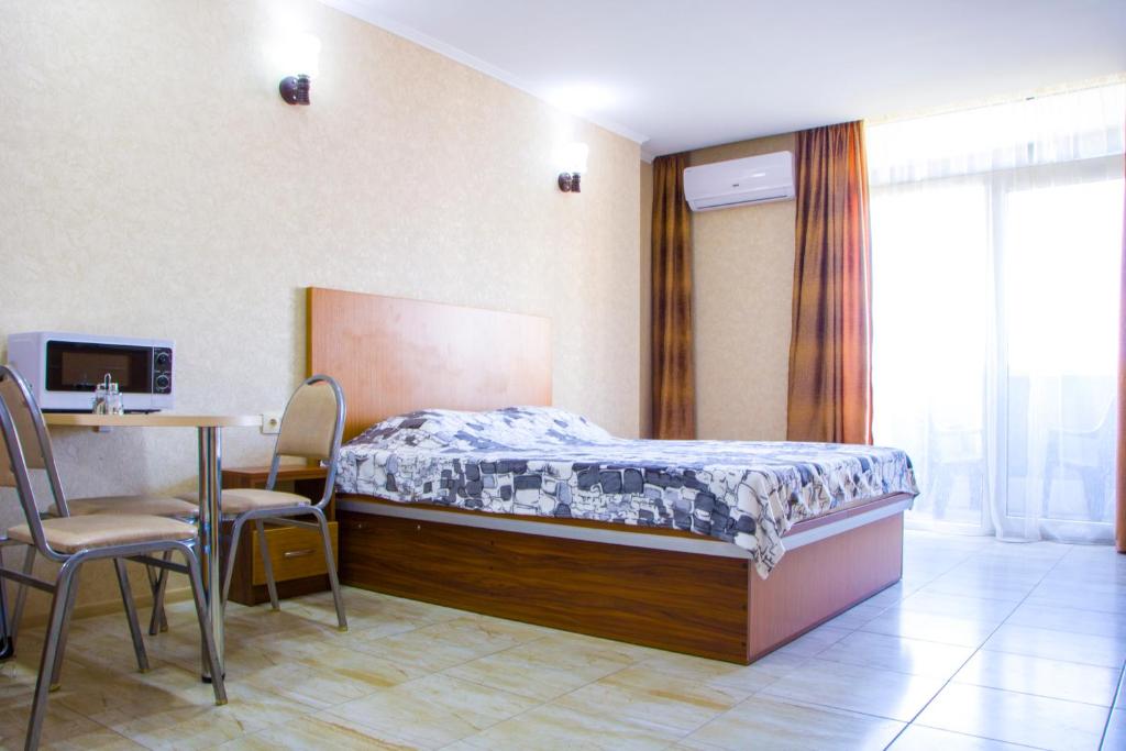 1 dormitorio con 1 cama, mesa y sillas en Apartment ZARINA in apart-otel RESIDENC en Batumi
