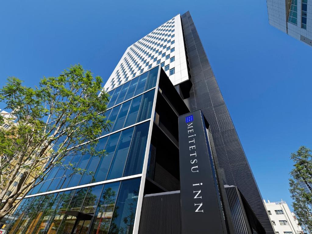 a tall building with a sign in front of it at Meitetsu Inn Nagoyaeki Shinkansenguchi in Nagoya