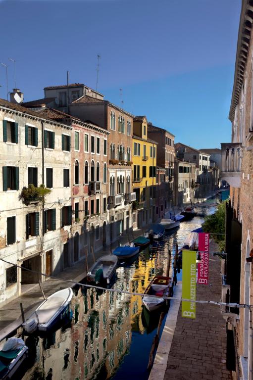 a group of boats in a canal between buildings at Hotel Pausania in Venice