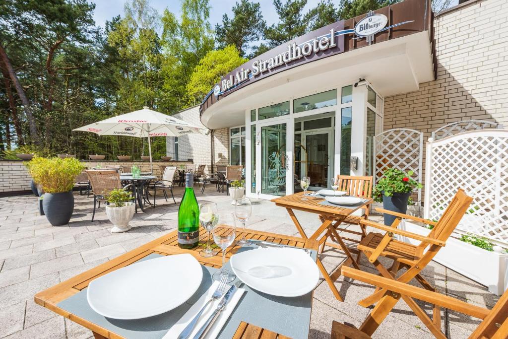 eine Terrasse mit Tischen und Stühlen vor einem Gebäude in der Unterkunft Bel Air Strandhotel Glowe in Glowe