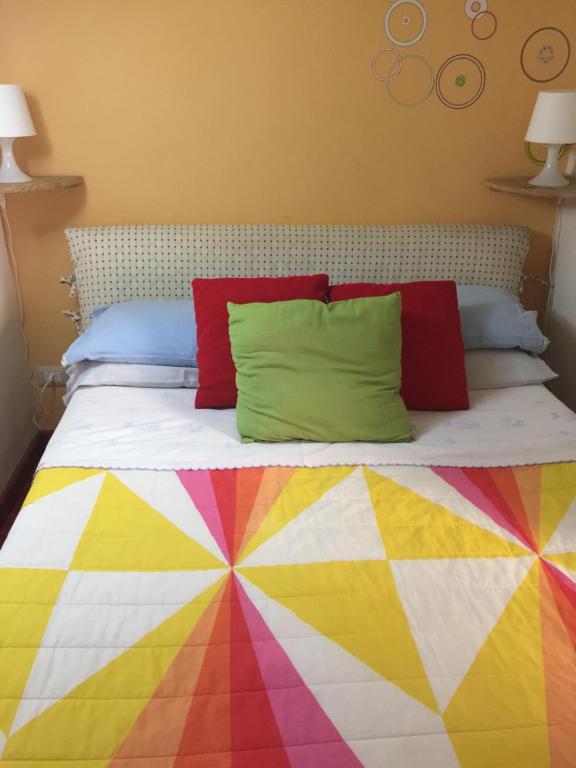 a bed with a multicolored blanket and pillows on it at Appartamento Rapisardi Centro in Catania