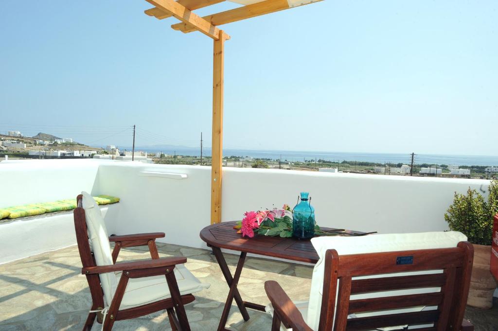 een tafel en stoelen op een patio met uitzicht op de oceaan bij Aigaio Studios tinos in Tinos Town