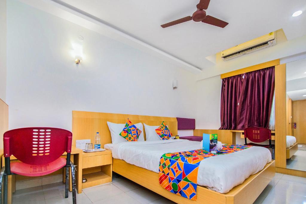 a bedroom with a bed and a red chair at FabExpress Picnic Plaza Mylapore in Chennai
