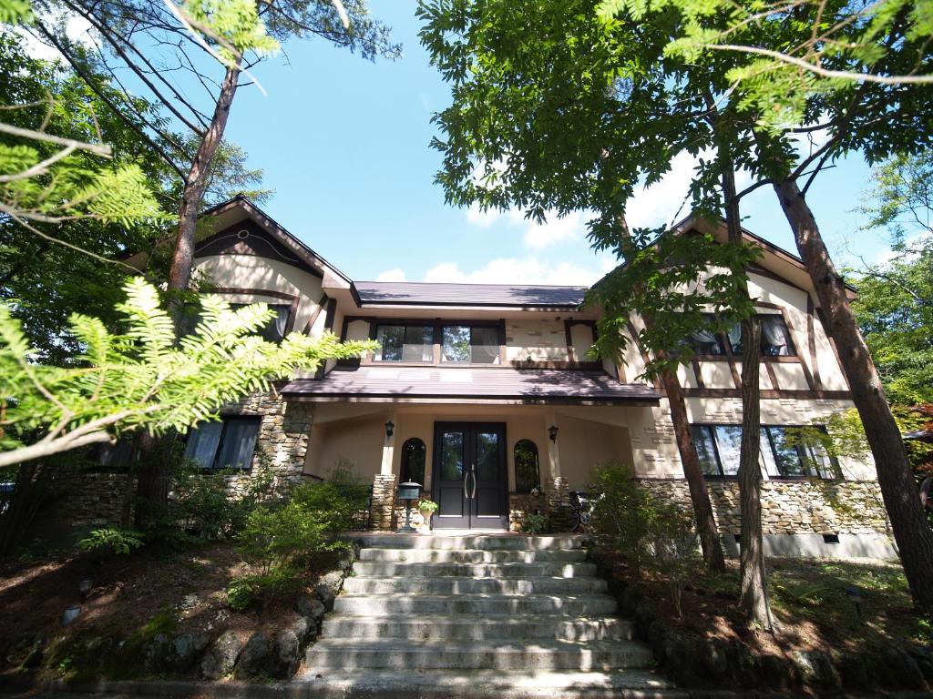 uma casa com escadas que levam até à porta da frente em ピッコロホテル オペラ軽井沢 em Karuizawa