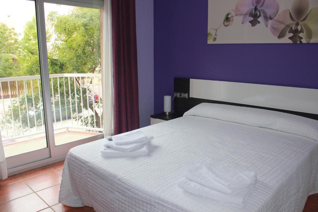 a bedroom with a white bed and a balcony at PISO EXTERIOR COMPLETO A 20 ' DE BARCELONA. in Sabadell