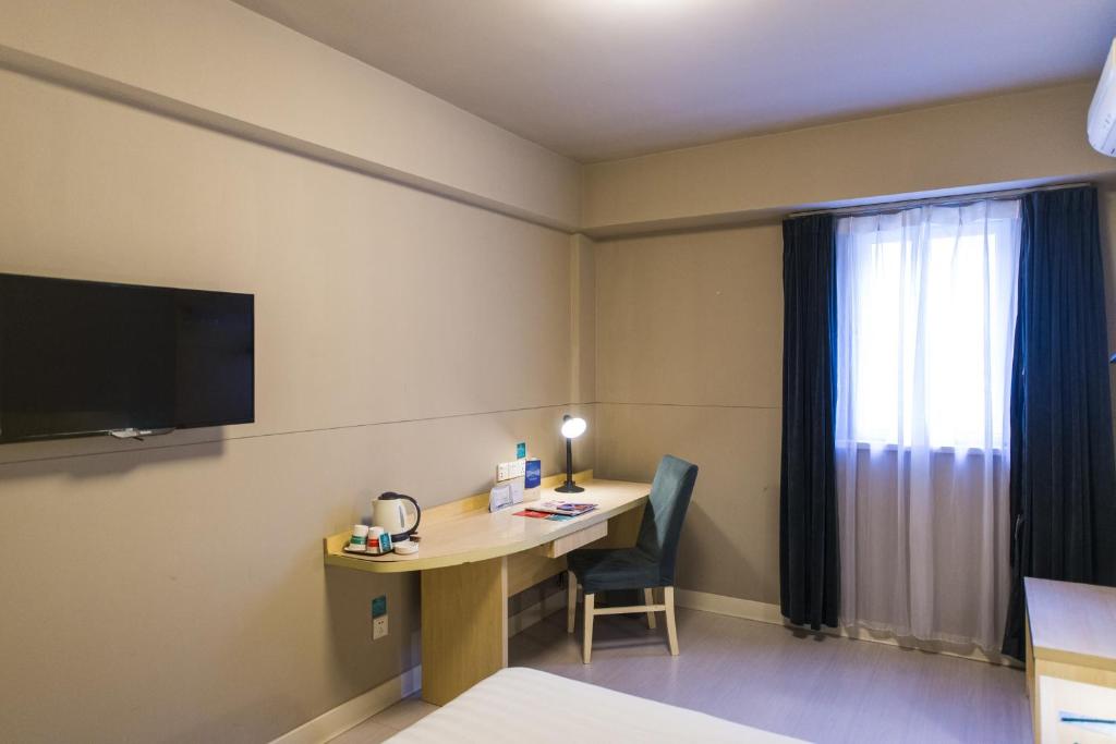 a hotel room with a desk and a television at Jinjiang Inn Style Xinyang Dongfanghong Avenue Cultural Centre in Xinyang