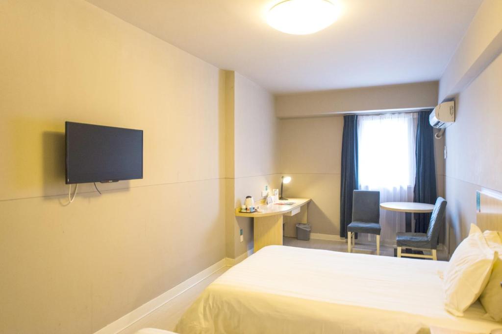 um quarto de hotel com uma cama e uma televisão na parede em Jinjiang Inn Select Shenqiu Administration Service Centre em Shicaoji