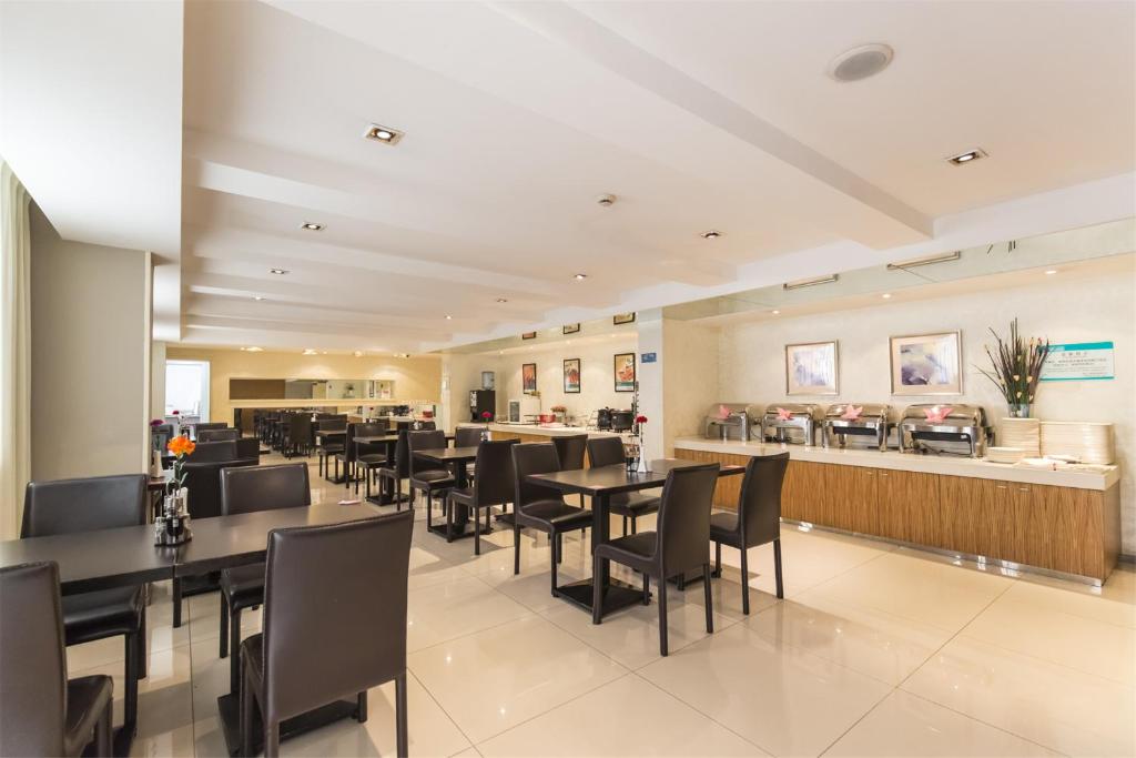 a restaurant with black tables and chairs and a counter at Jinjiang Inn Style Huangshan Train station Old Street in Huangshan