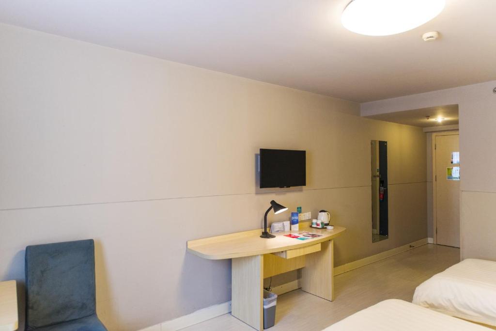 a room with a desk and a bed and a tv at Jinjiang Inn Select Wuxi Donglin Square Metro Station in Shanyang