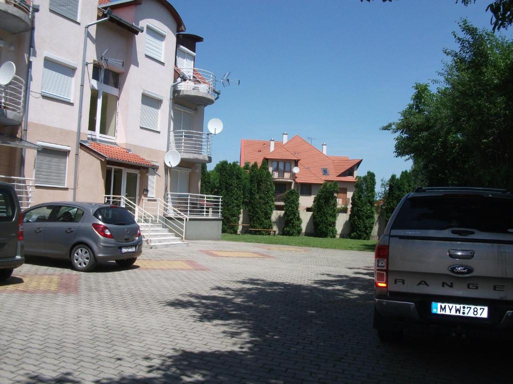 two cars parked in a parking lot in front of a building at Csorvy Apartman in Hajdúszoboszló